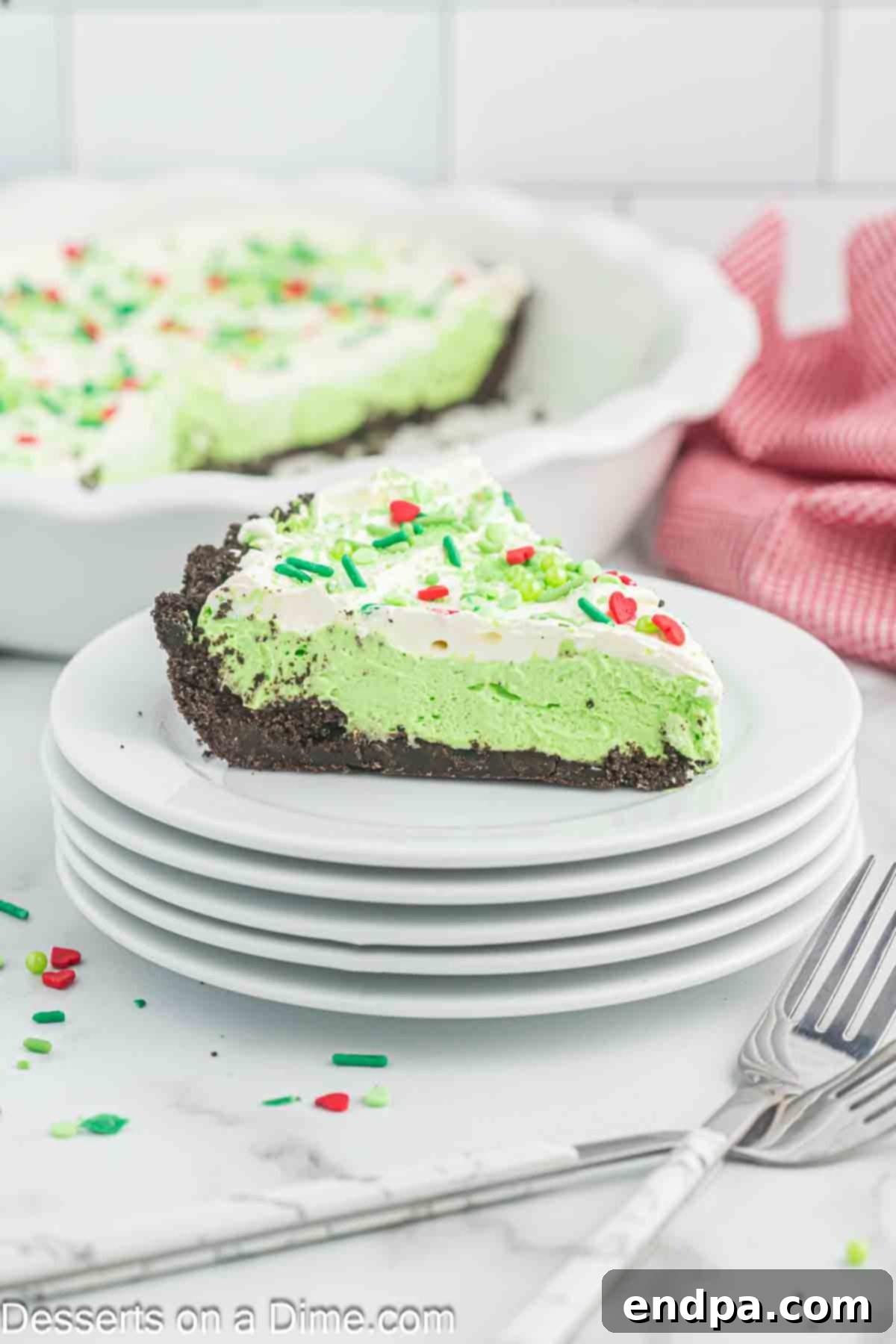 Slice of Grinch pie on a plate, showcasing its green filling and chocolate crust.