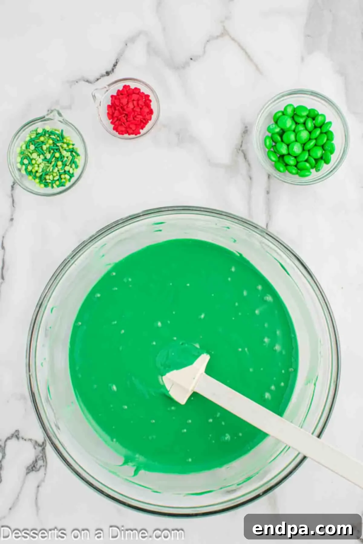 Melting green chocolate candy melts in a clear glass bowl in the microwave.