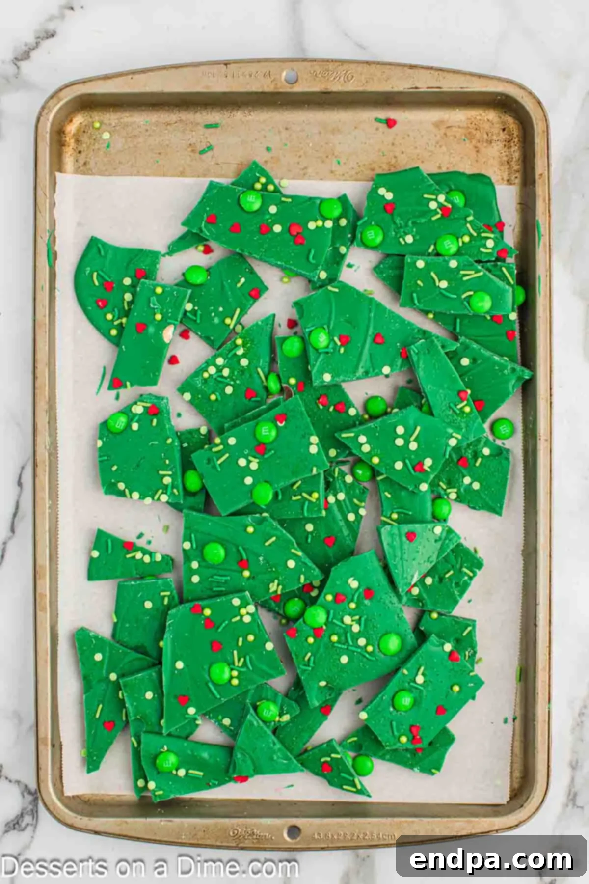 Broken pieces of Grinch Bark, showcasing the green and red colors, in a white bowl.