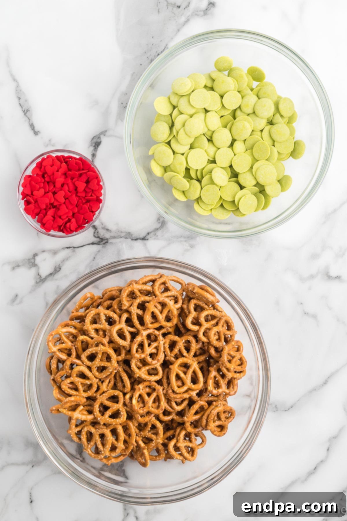 Ingredients for grinch pretzels - Mini Pretzel Twists, candy melts, red heart sprinkle