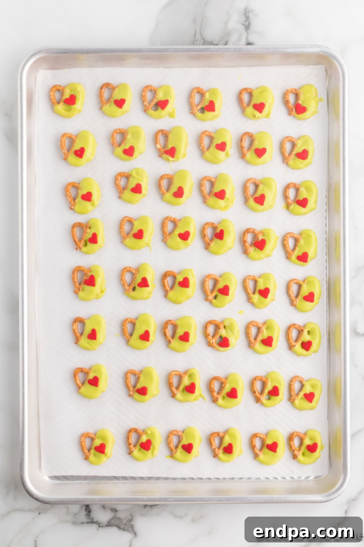 Placing the pretzel bites on a baking sheet and topped with a red heart sprinkle