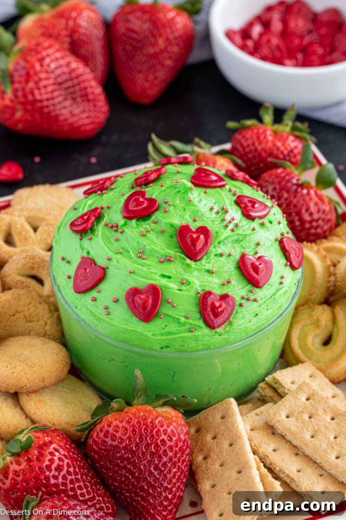 Heart-Growing Grinch Dip 2 Grinch dip in a bowl with various dippers arranged around it, showcasing its festive appeal.