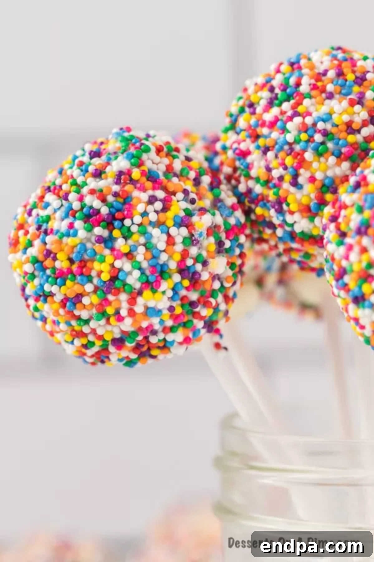 Beautifully decorated cake pops with colorful sprinkles, presented upright in a charming mason jar.