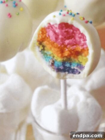 Crafting Irresistible Cake Pops 8 A vibrant Rainbow Cake Pop, revealing colorful layers inside with sprinkles on top.