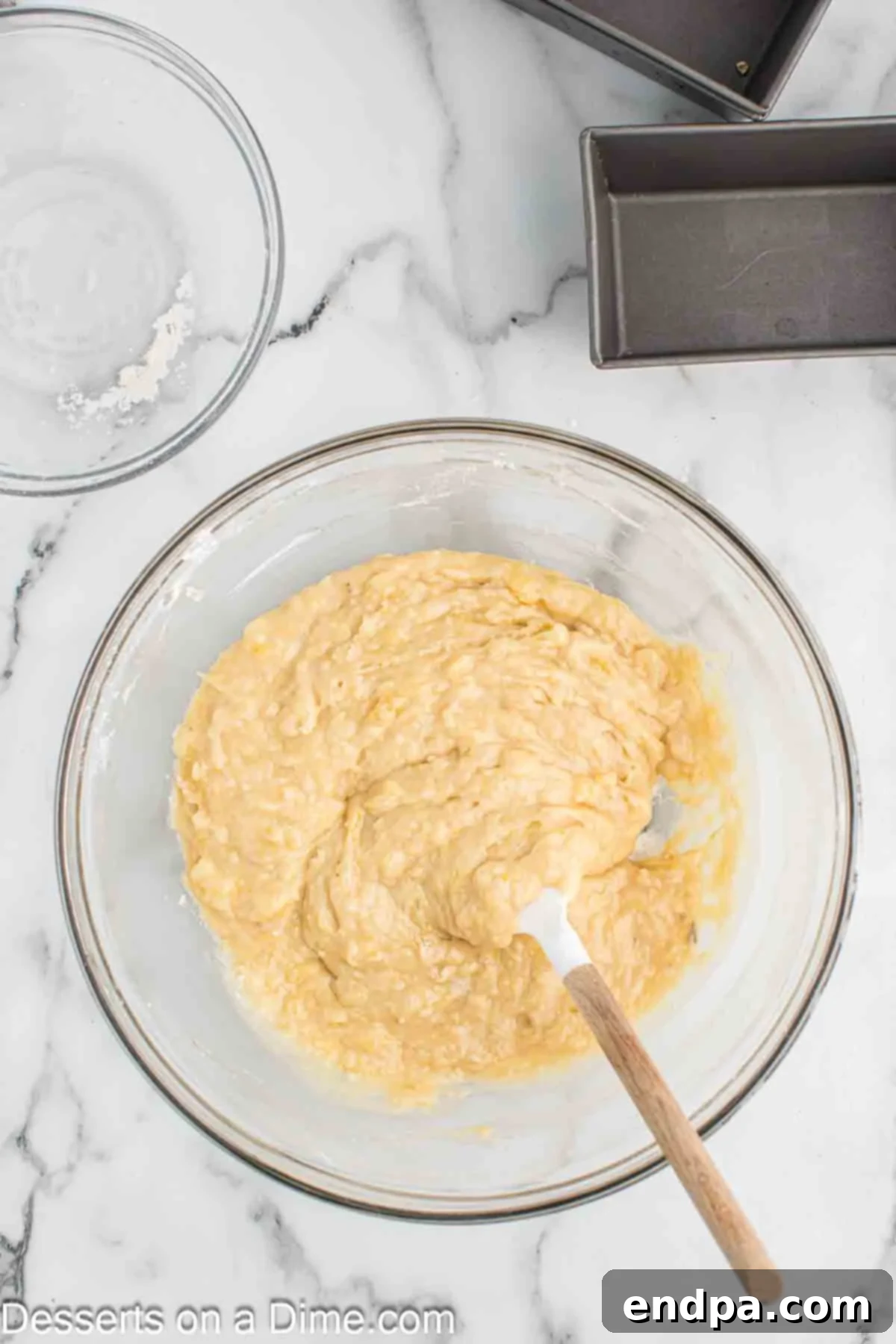 Golden Air Fryer Banana Loaf 5 Dry ingredients being added to the wet mixture in a bowl for banana bread batter.