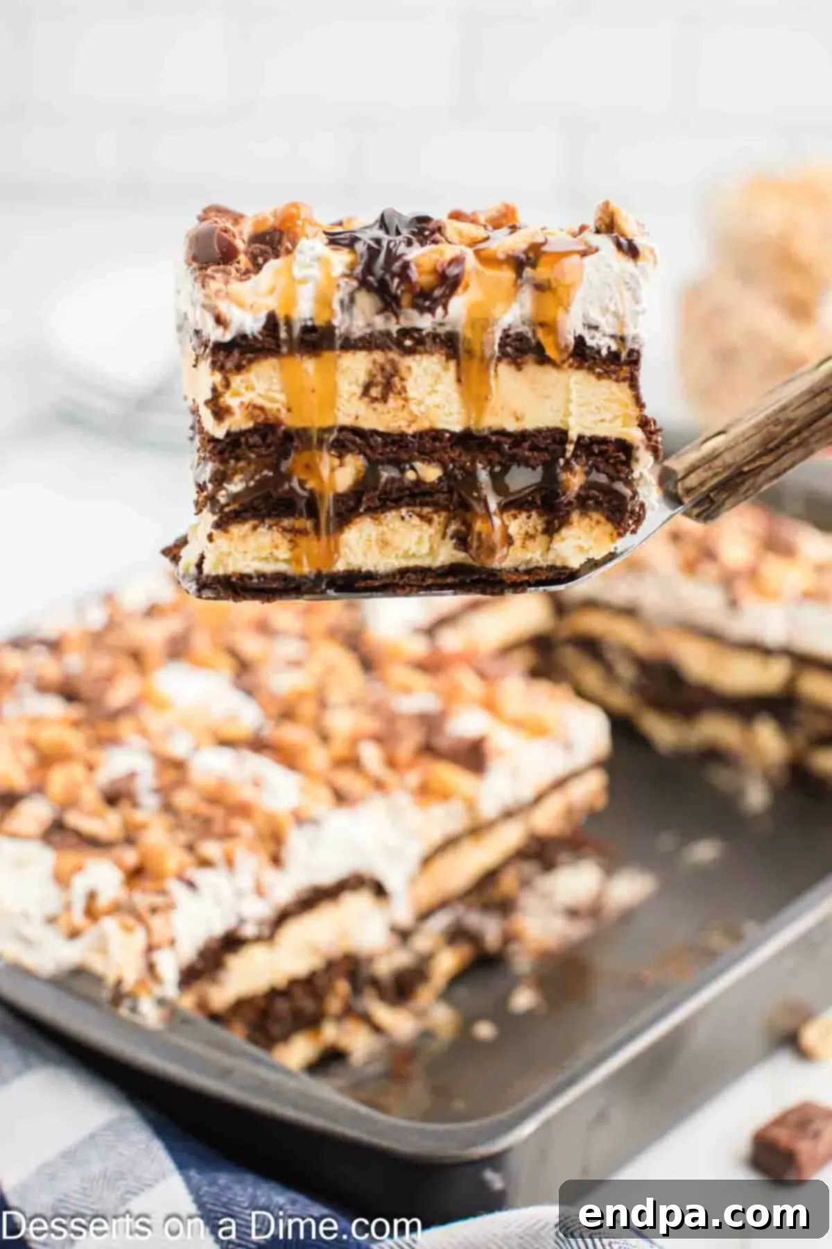 Ultimate Snickers Ice Cream Cake 2 A slice of Snickers Ice Cream Cake being served, showcasing its many delicious layers of ice cream, chocolate, caramel, and Snickers pieces.