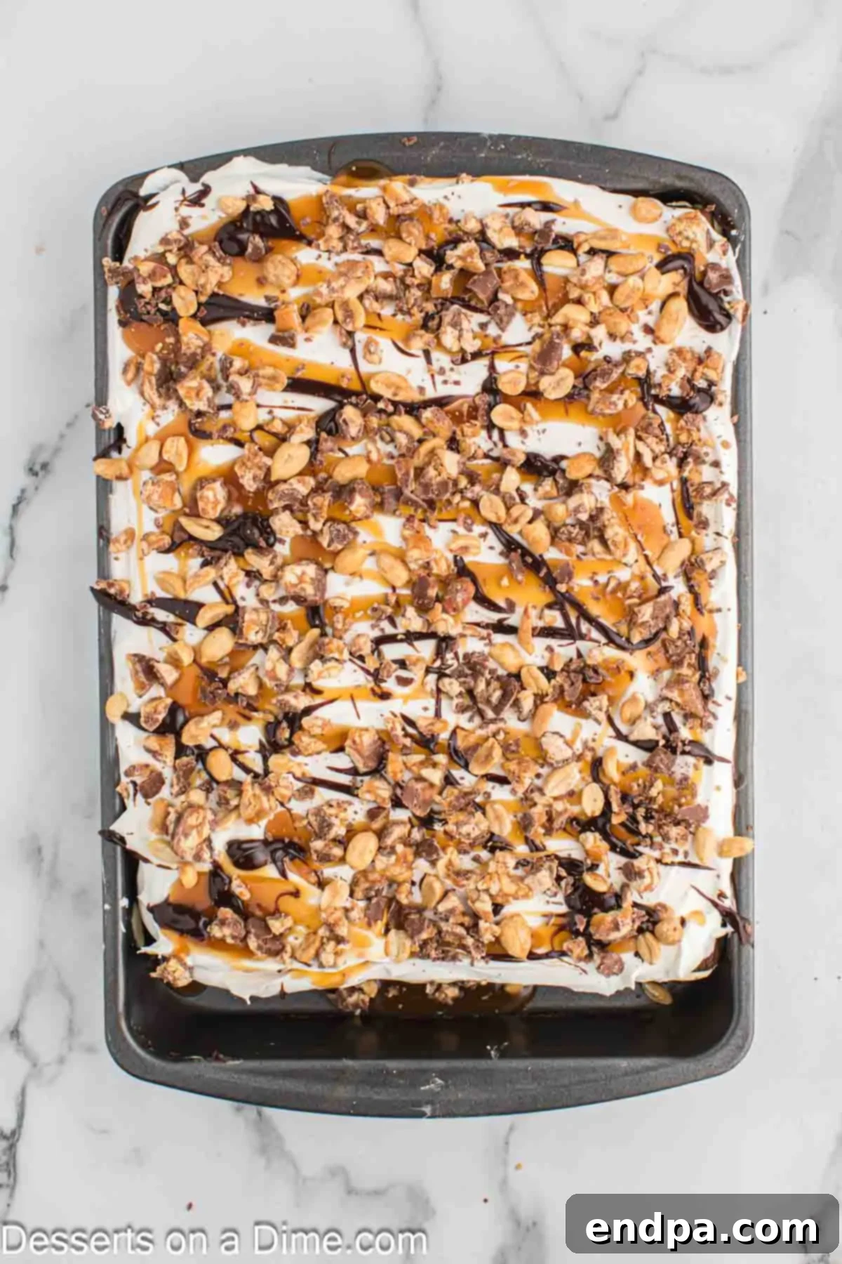 Ultimate Snickers Ice Cream Cake 11 A freshly frozen Snickers ice cream cake being carefully removed from the freezer, ready to be sliced and served.