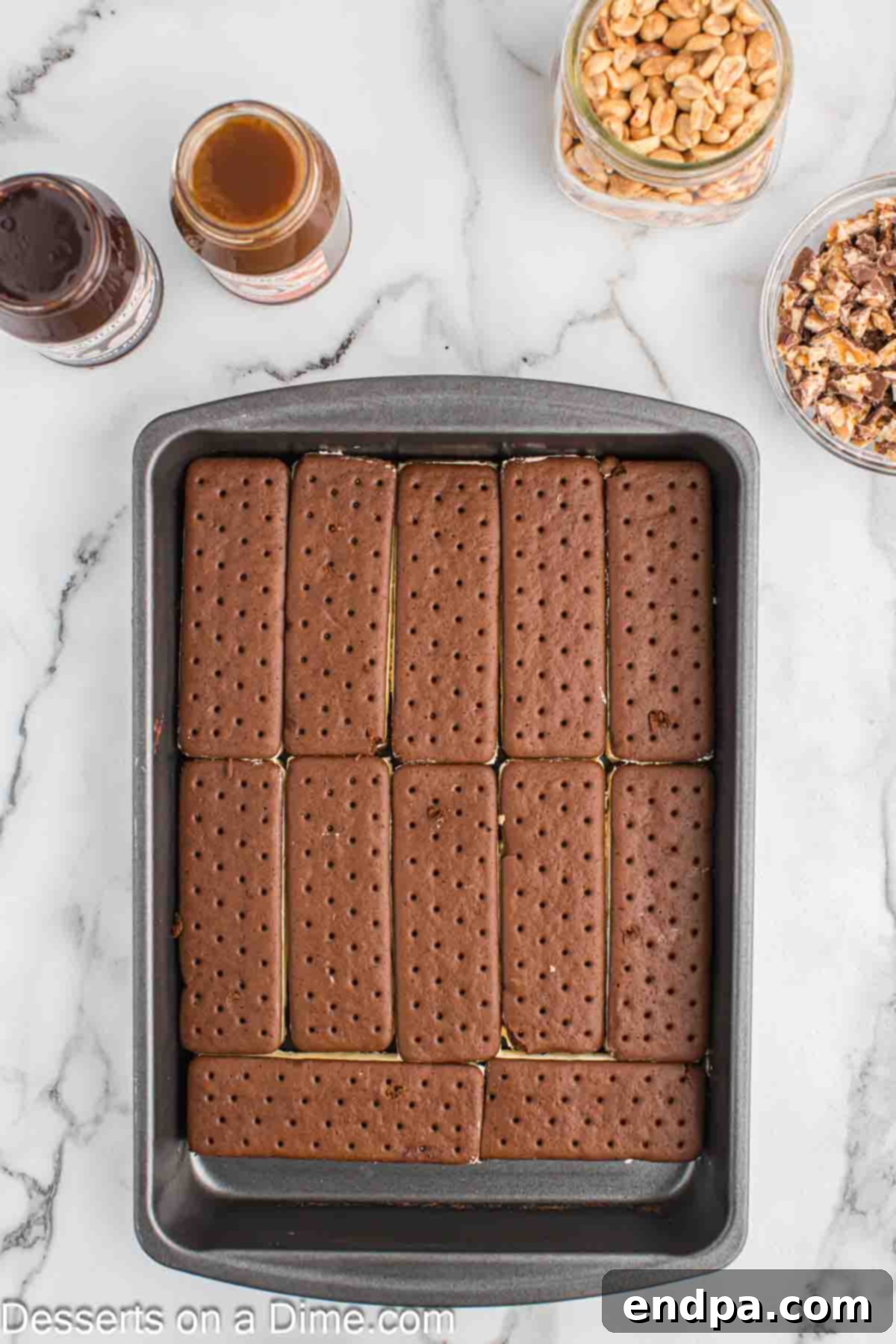 Ultimate Snickers Ice Cream Cake 4 First layer of ice cream sandwiches perfectly arranged at the bottom of a 9x13 inch baking dish, forming a solid base.