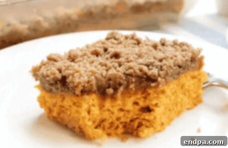 A square slice of pumpkin coffee cake with a crumb topping.