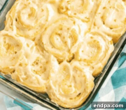 Orange rolls on a white plate with orange glaze.