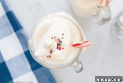 A mug of creamy white hot chocolate garnished with whipped cream and chocolate shavings.