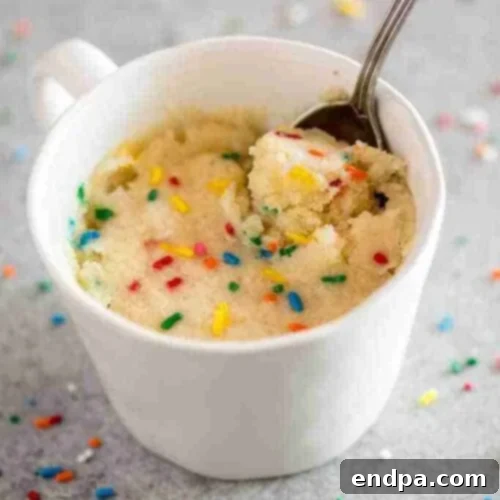 A vanilla mug cake garnished with whipped cream and sprinkles.