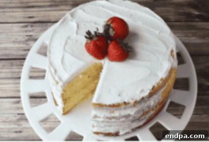 A slice of moist vanilla cake with creamy white frosting.