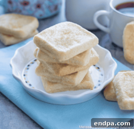 Vanilla shortbread cookies stacked next to a cup of tea.
