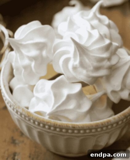 Light and delicate meringue cookies, stacked on a plate.
