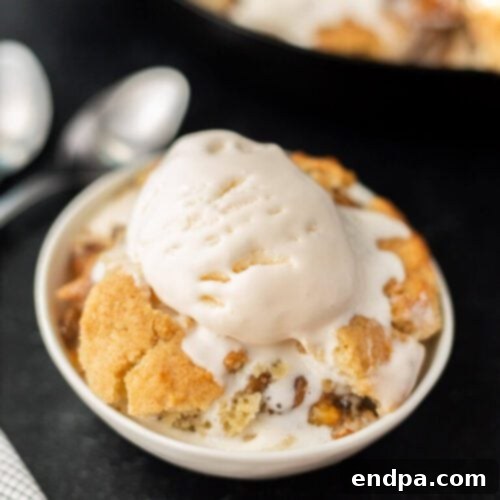 A rustic Grilled Peach Cobbler served hot from a cast iron skillet.