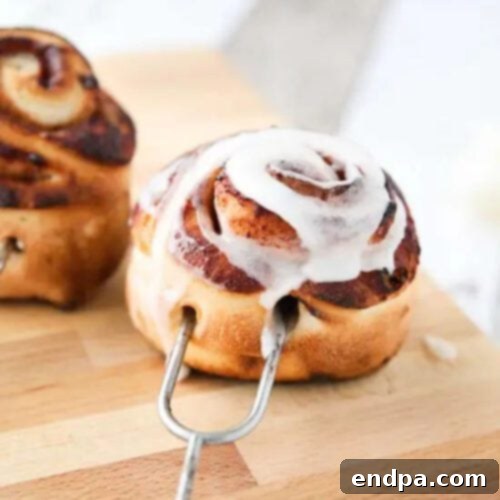 Golden-brown Campfire Cinnamon Rolls cooked over an open fire on sticks.