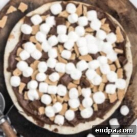 A slice of Campfire Dessert Pizza topped with melted marshmallows, chocolate, and graham crackers.