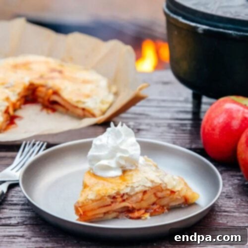 A golden-brown Dutch Oven Apple Pie with a lattice crust, fresh out of the campfire.