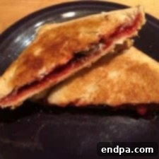 A golden-brown Chocolate Cherry Pudgy Pie, cooked in a pie iron over a campfire.