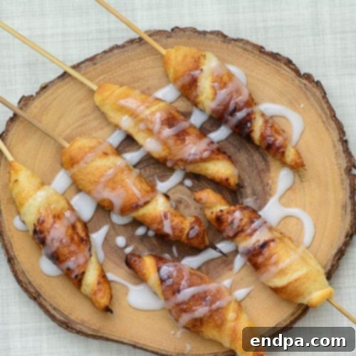 Golden-brown Campfire Cinnamon Roll-Ups, spiraled on sticks and ready to eat.