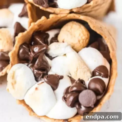 S'mores Campfire Cones filled with melted chocolate and marshmallows, prepared in foil cones.