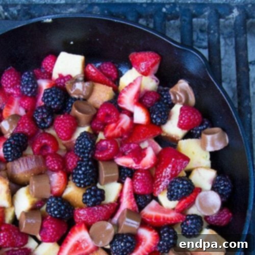 A warm Pound Cake and Berry Campfire Skillet Dessert, bubbling with fresh berries in a cast iron skillet.