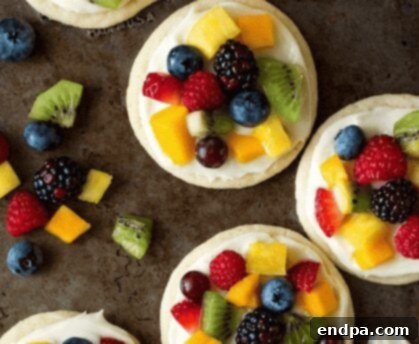 Sweet Success Treats 7 A large sugar cookie fruit pizza topped with various fresh fruits and a creamy white frosting.