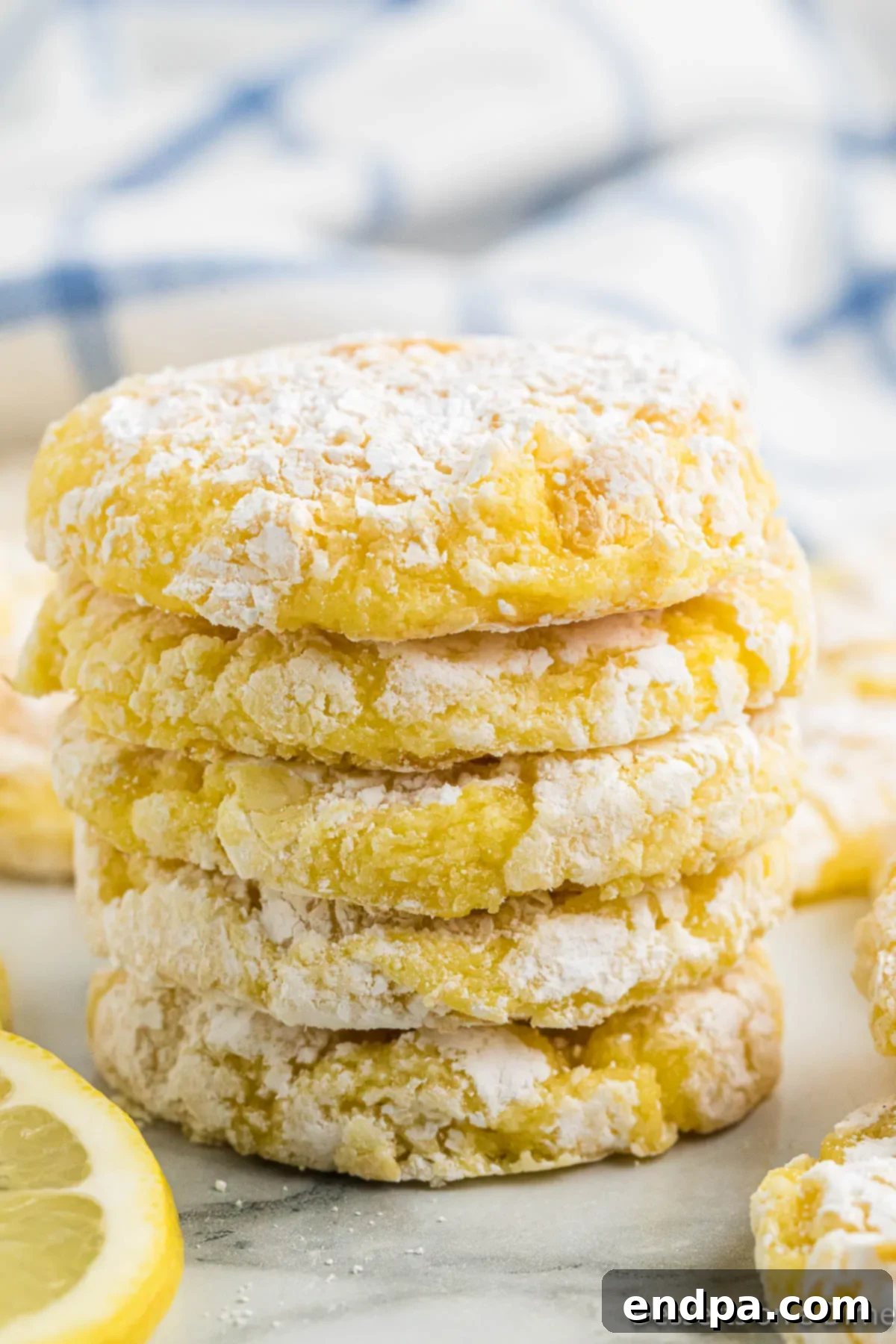 Lemon cookies stacked together, showcasing their soft, crinkly texture and powdered sugar coating.