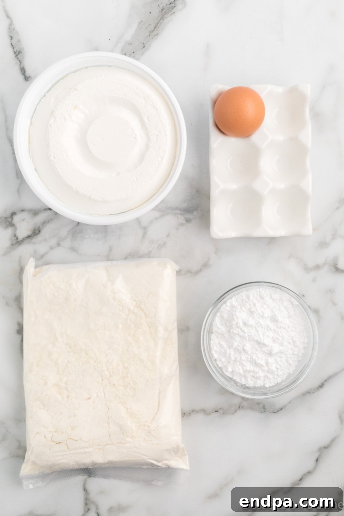 Four key ingredients for lemon cake mix cookies: lemon cake mix, cool whip, an egg, and powdered sugar.