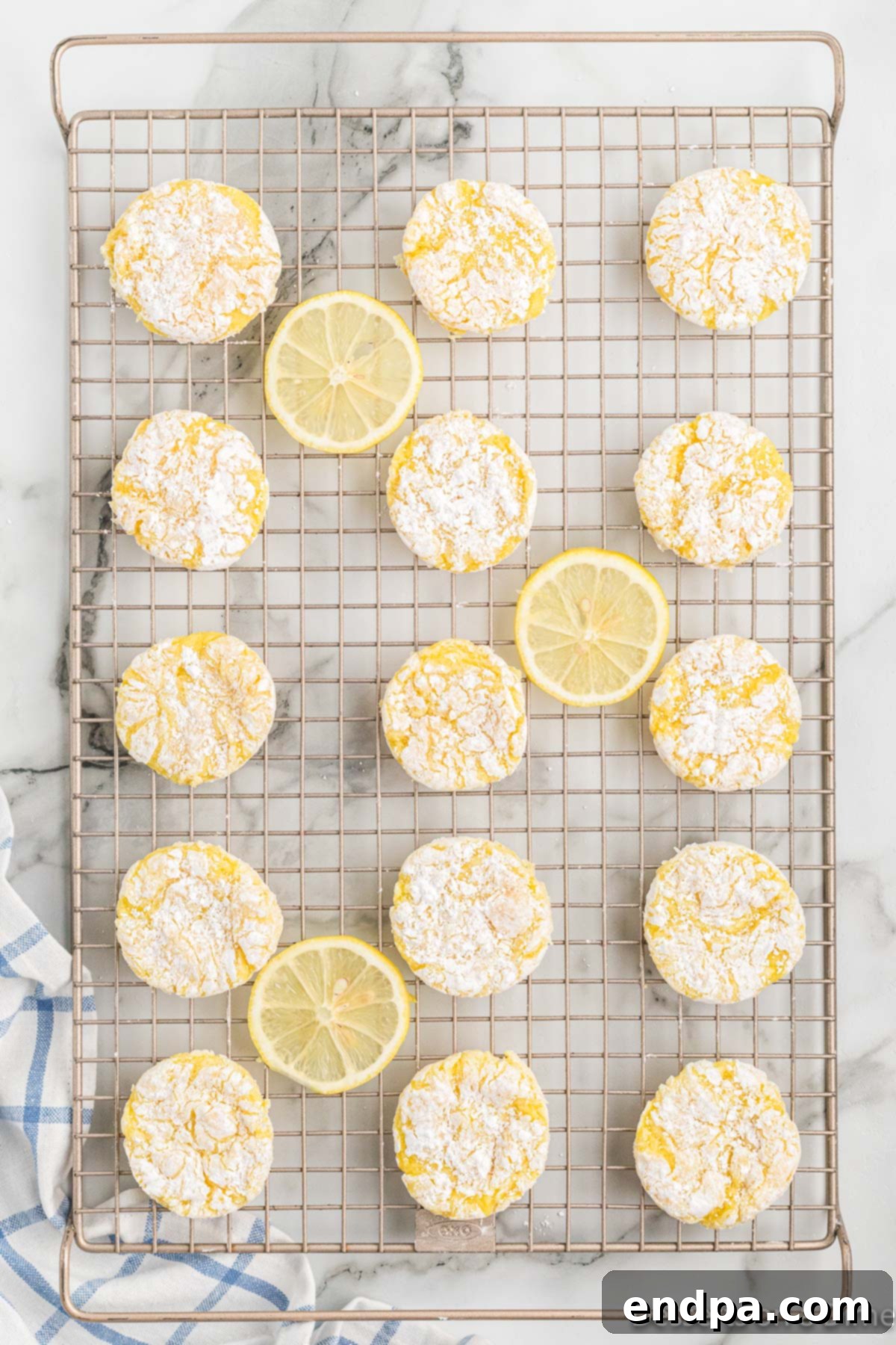 Freshly baked lemon cookies cooling on a wire rack after being removed from the baking sheet.