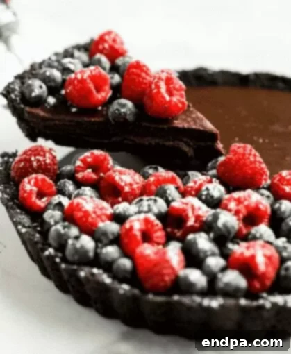 No Bake Chocolate Tart topped with fresh berries and powdered sugar.