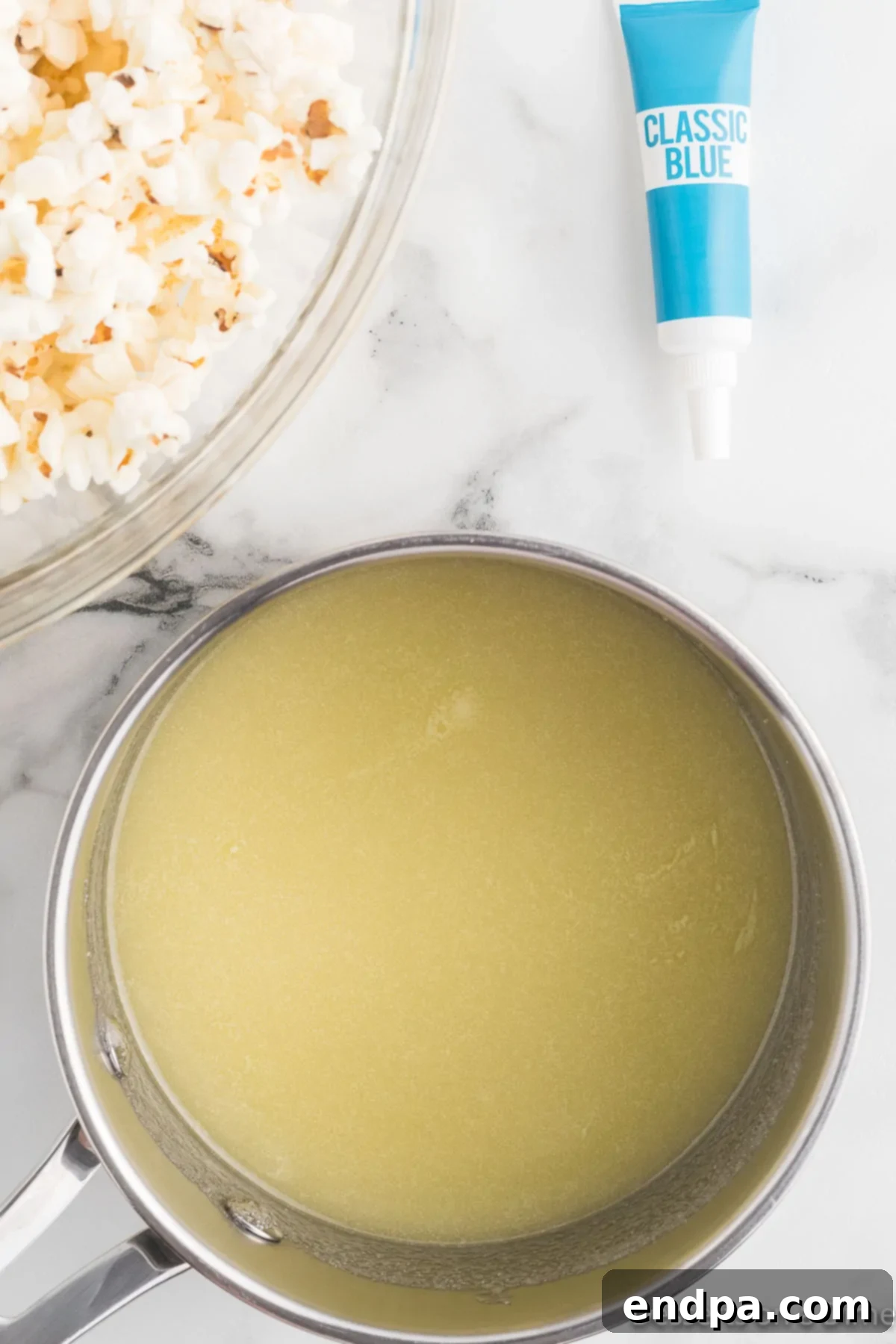 Saucepan with sugar, water, and melted butter mixture beginning to simmer on a stove.