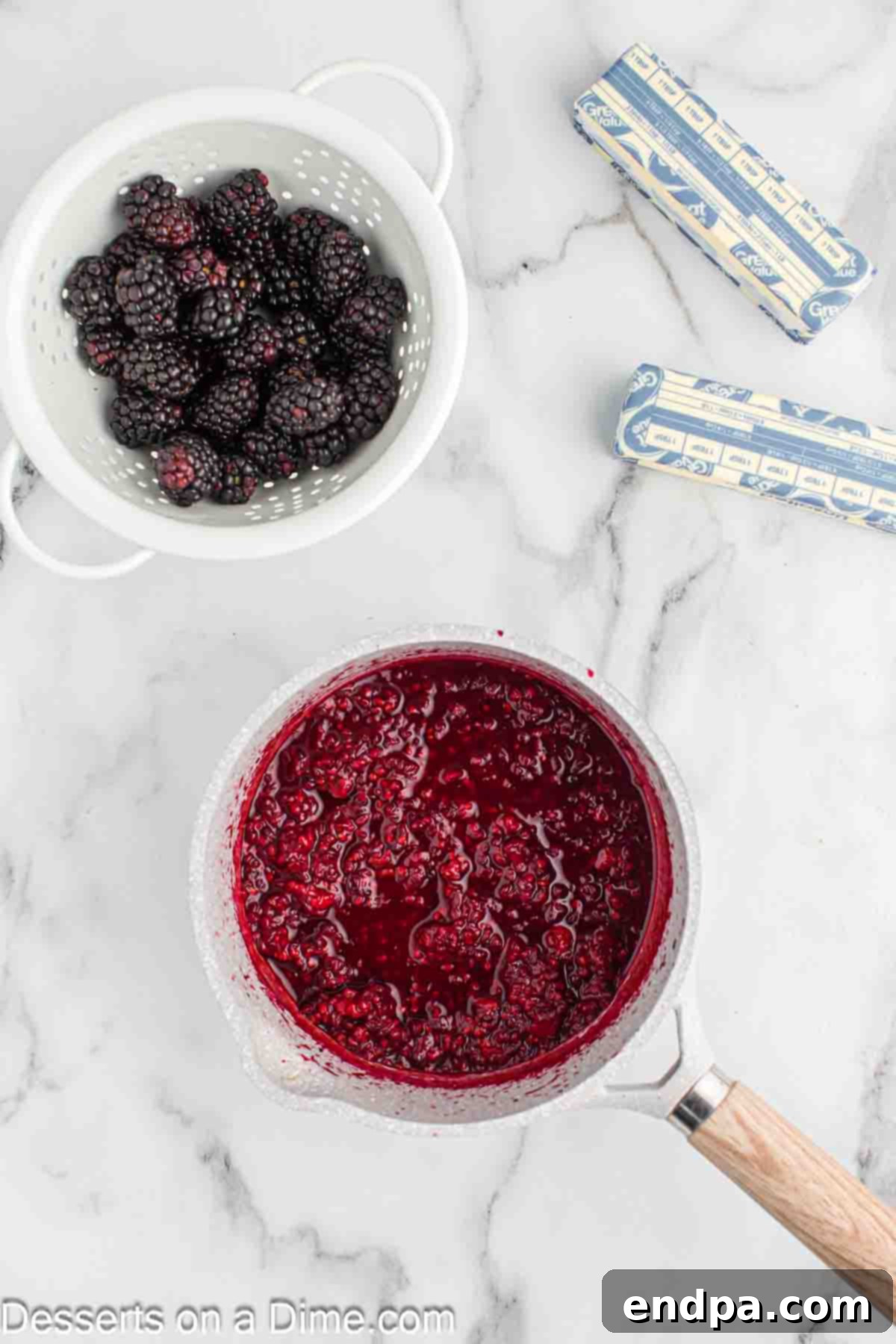 Blackberries and lemon juice gently simmering in a small saucepan on the stove, beginning to break down into a puree.