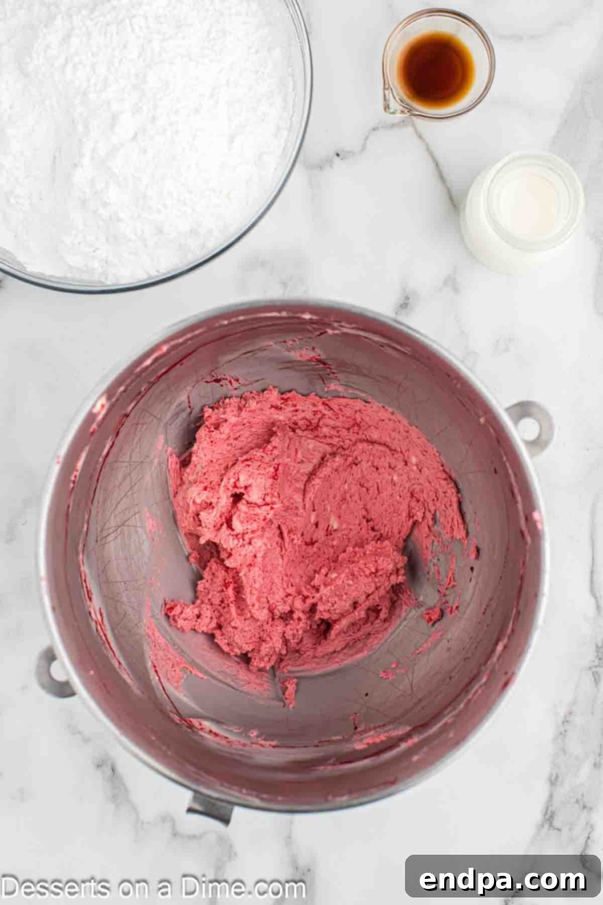Softened butter and the cooled blackberry mixture being creamed together in a large mixing bowl with a stand mixer.