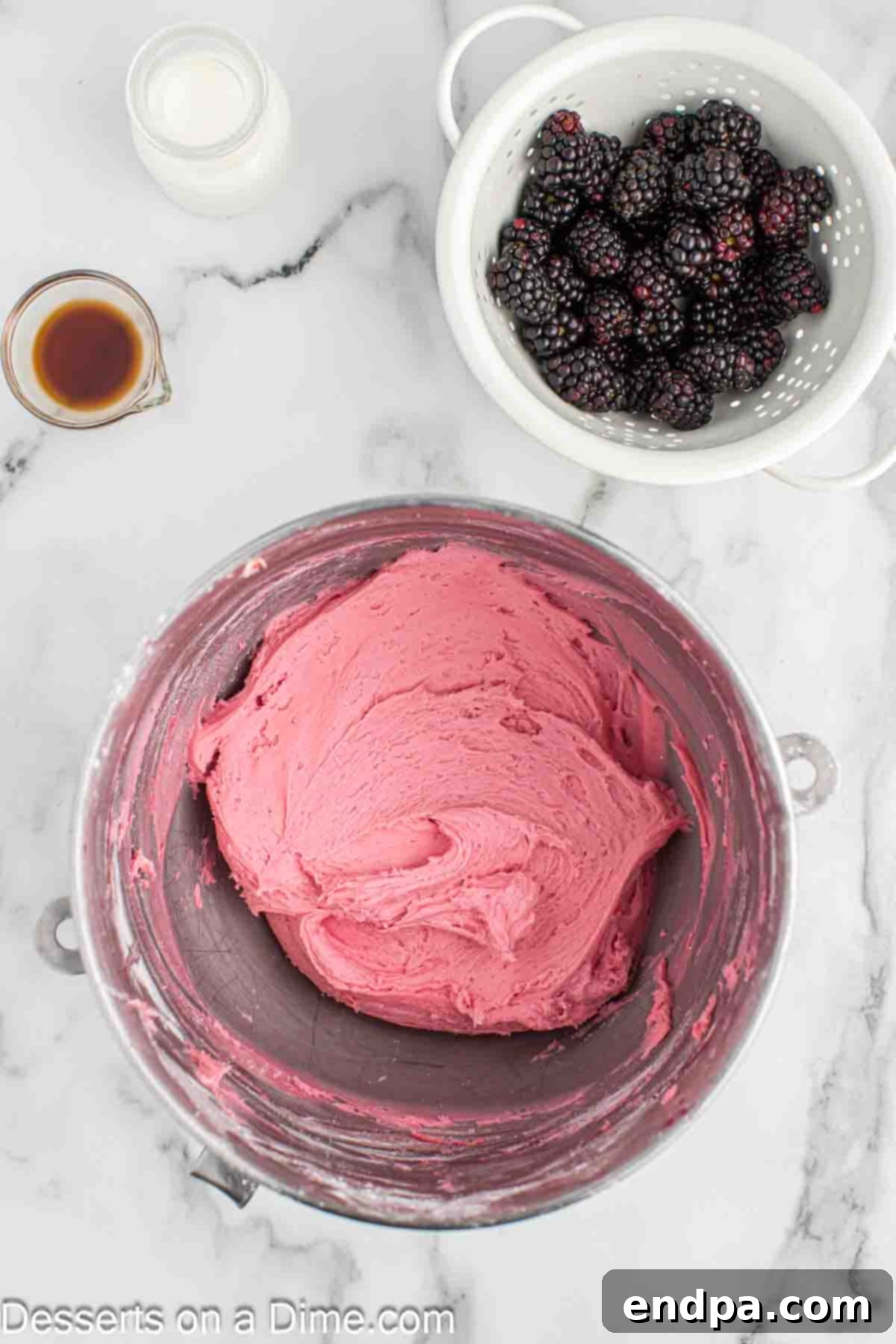 Powdered sugar being gradually added to the blackberry and butter mixture in a mixing bowl, creating a light purple frosting.
