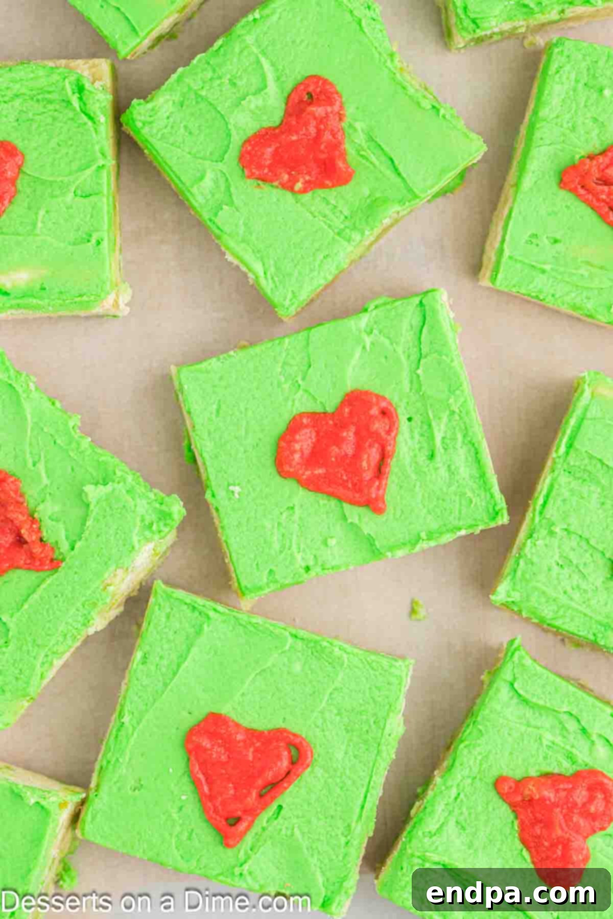 Delicious Grinch Cookie Bars cut into perfect squares, showcasing their vibrant green frosting and tiny red hearts.