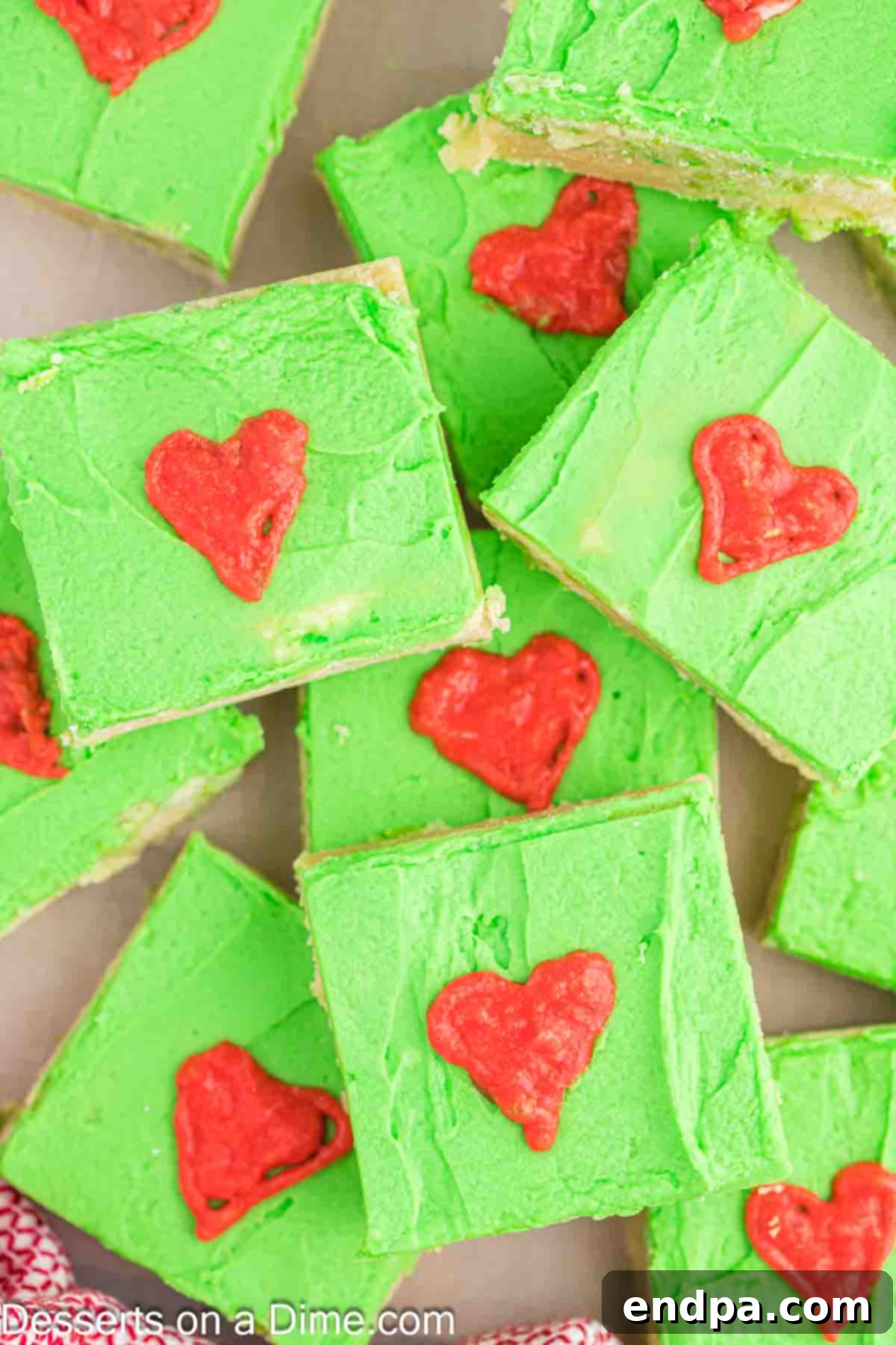 A close-up view of a tray of freshly baked and decorated Grinch Cookie Bars, cut into perfect squares, ready to be enjoyed.