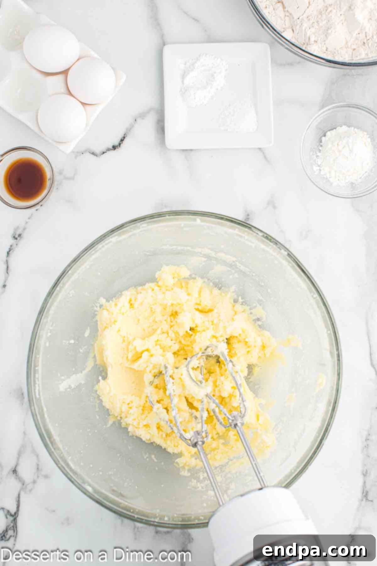 Softened butter and granulated sugar being creamed together in a mixing bowl until light and fluffy.