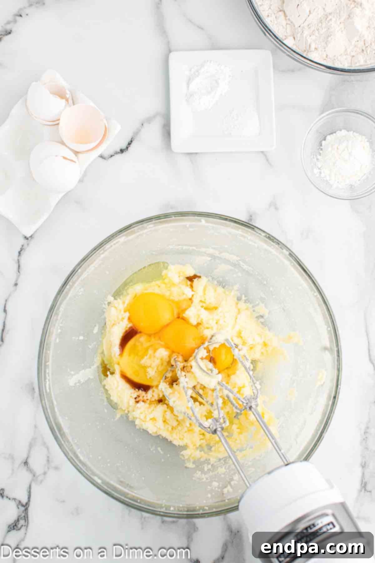 Room temperature eggs and vanilla extract being added to the creamed butter and sugar mixture.