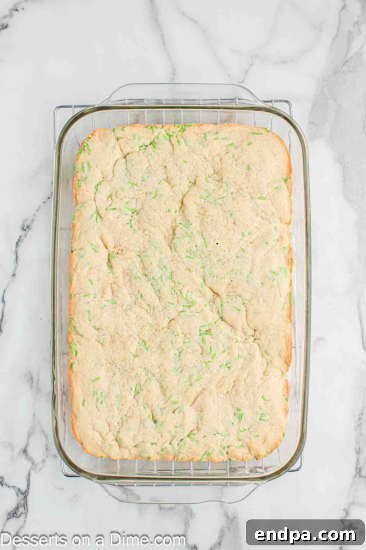 Freshly baked Grinch cookie bars cooling on a wire rack after being removed from the oven.