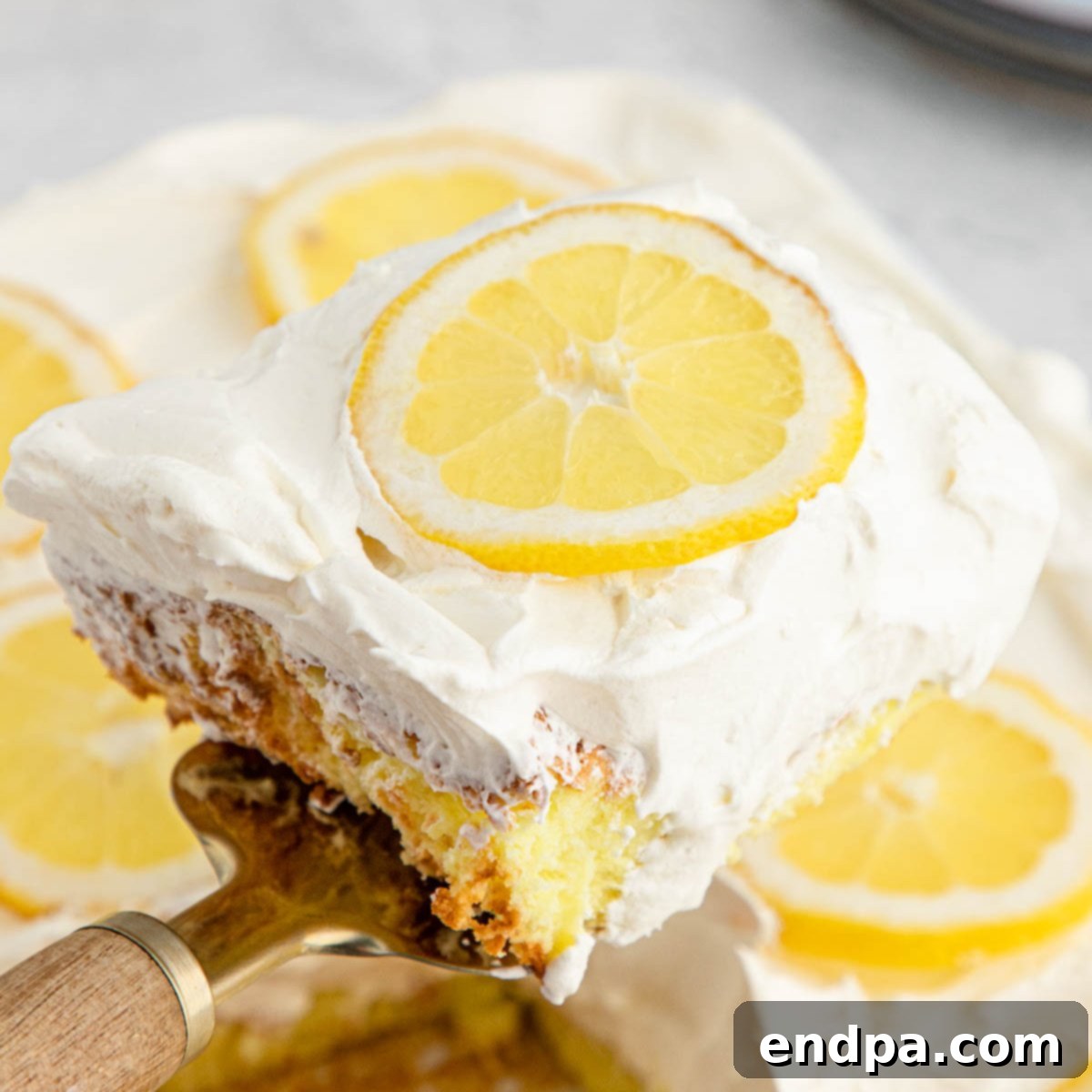 Sunshine Lemon Angel Delight 9 Lemon Angel Food Cake cut and served on a plate with whipped cream and lemon slices.