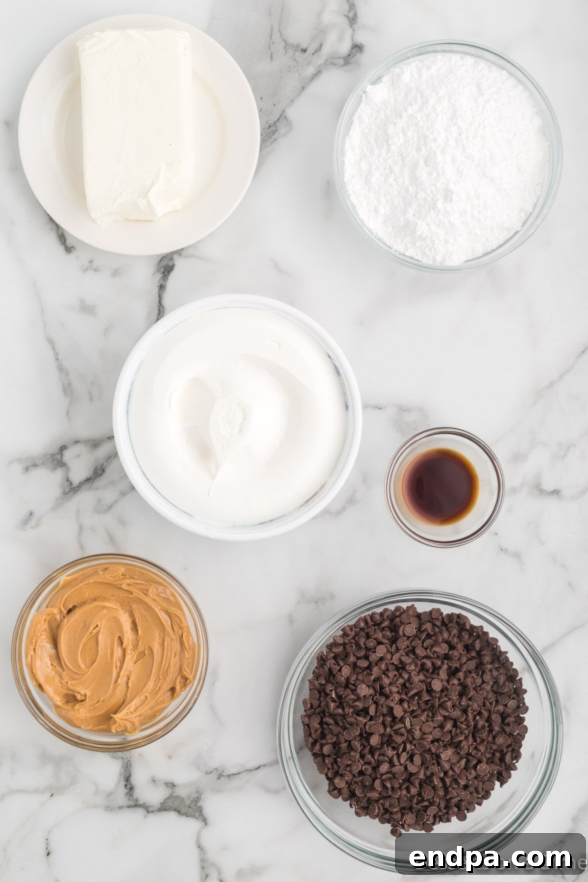 Dreamy Peanut Butter Chocolate Dip 3 A flat lay of all the essential ingredients for Buckeye Dip: softened cream cheese, sifted powdered sugar, creamy peanut butter, pure vanilla extract, a tub of whipped topping, and a bowl of mini chocolate chips.