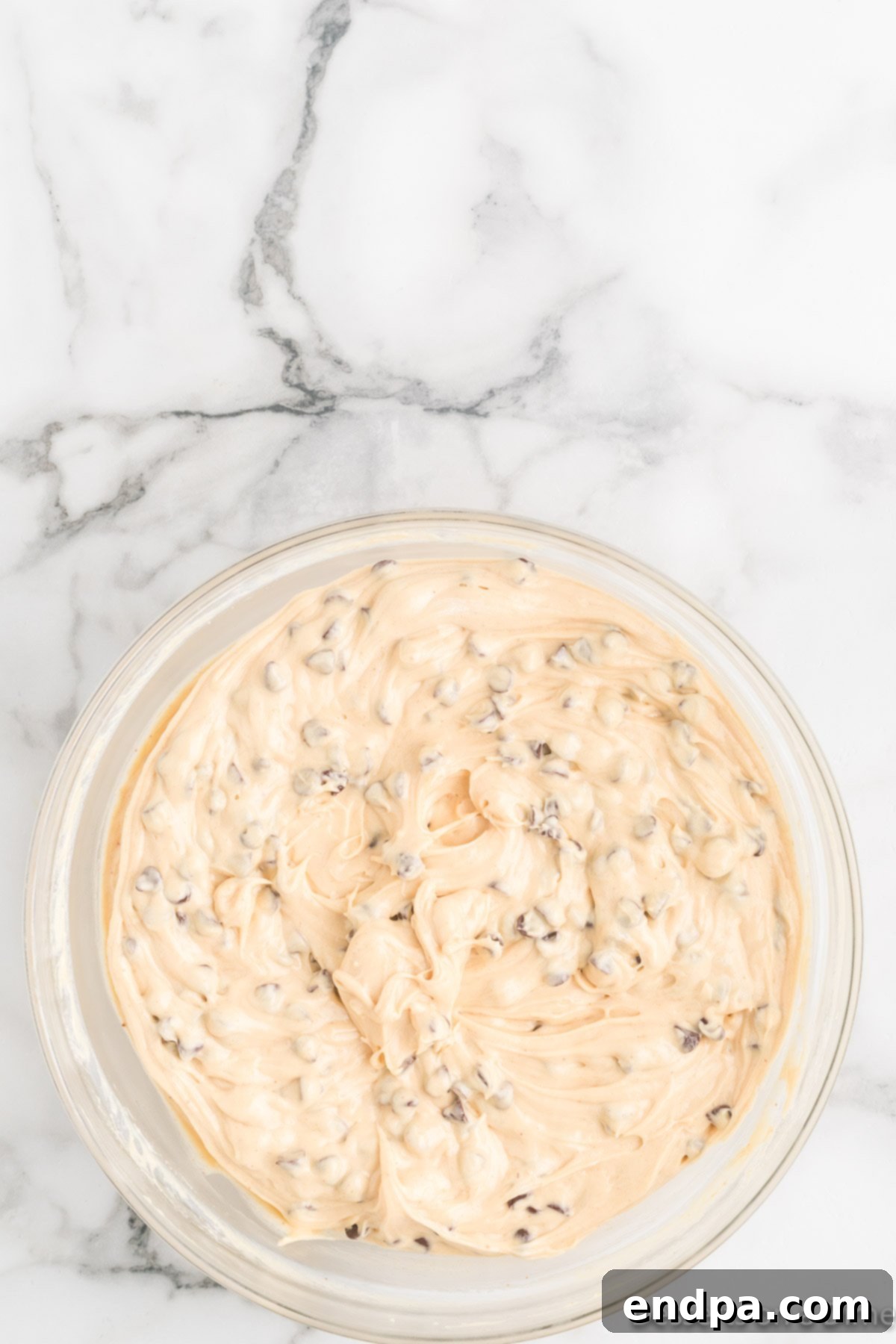 Dreamy Peanut Butter Chocolate Dip 6 Mini chocolate chips being gently folded into the creamy Buckeye Dip mixture in a bowl, preparing for the final chilling stage.