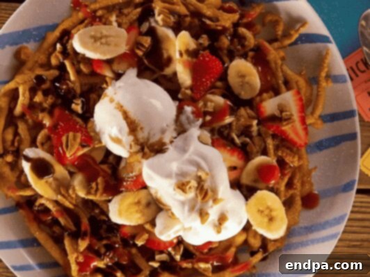 Banana Split Funnel Cake, combining classic carnival dessert with fresh fruit and syrup.