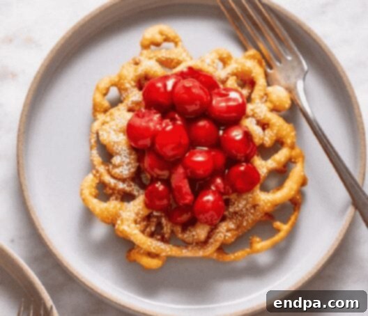 Tart Cherry Funnel Cake Sundae, topped with powdered sugar, tart cherries, and vanilla ice cream.