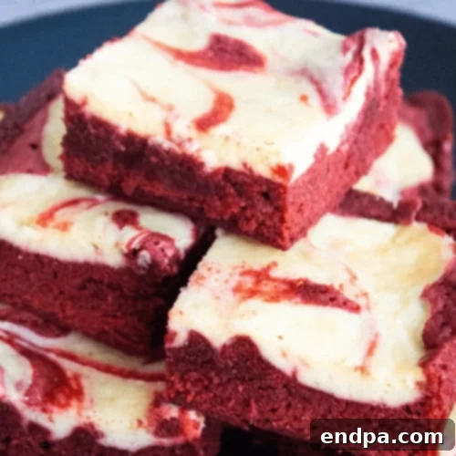 29 Irresistible Red Velvet Desserts 3 Red velvet cheesecake bars, featuring a rich red base swirled with creamy cheesecake, cut into neat squares.