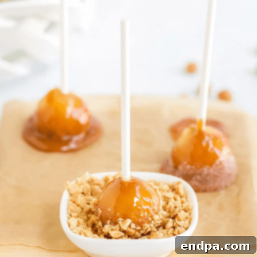 Mini caramel apples with toppings in a dish.