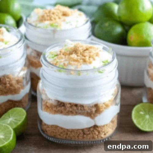 44 Refreshing No-Bake Summer Treats 10 Bright green Key Lime Pie Trifle in a clear glass bowl, showing distinct layers of creamy filling and graham cracker crumbs, topped with lime slices.