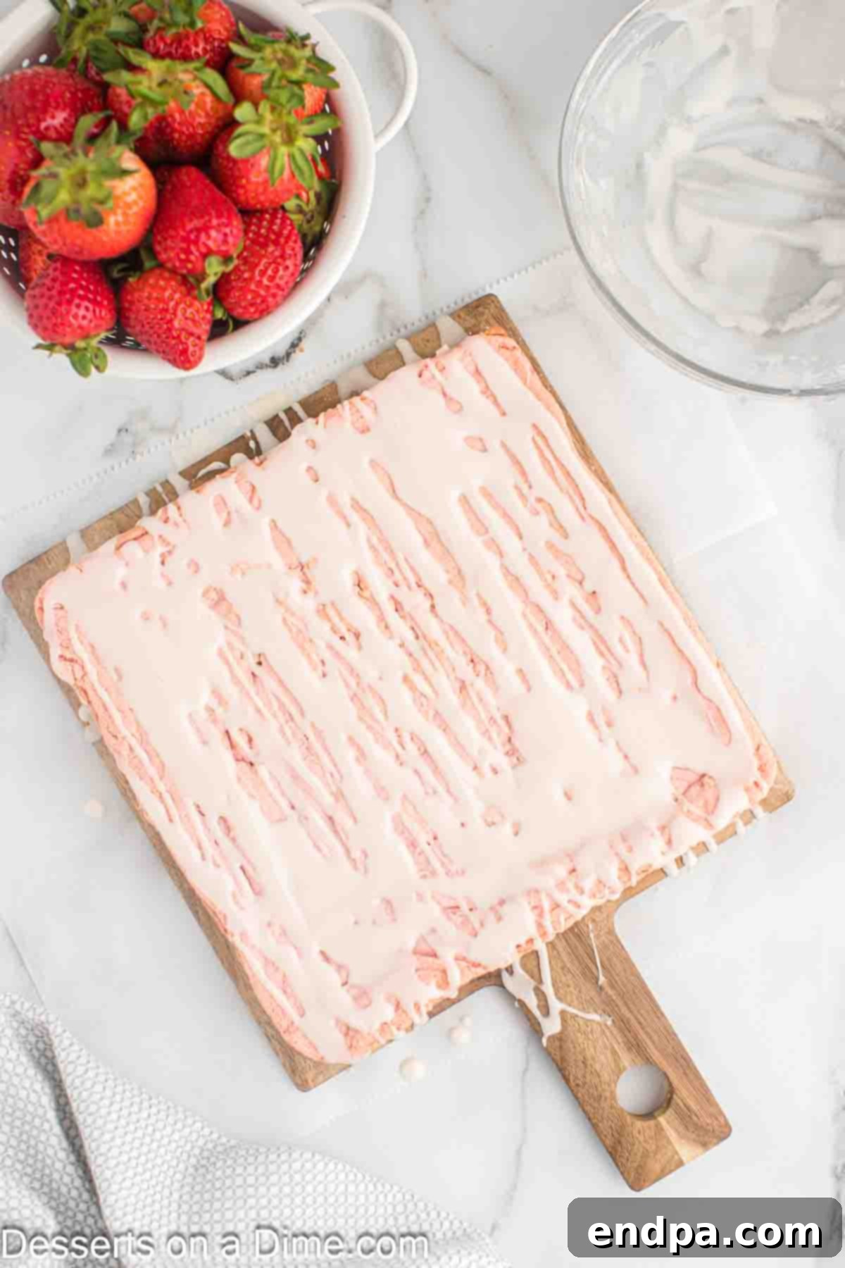 Sweet glaze being drizzled over cooled strawberry brownies in the baking dish.